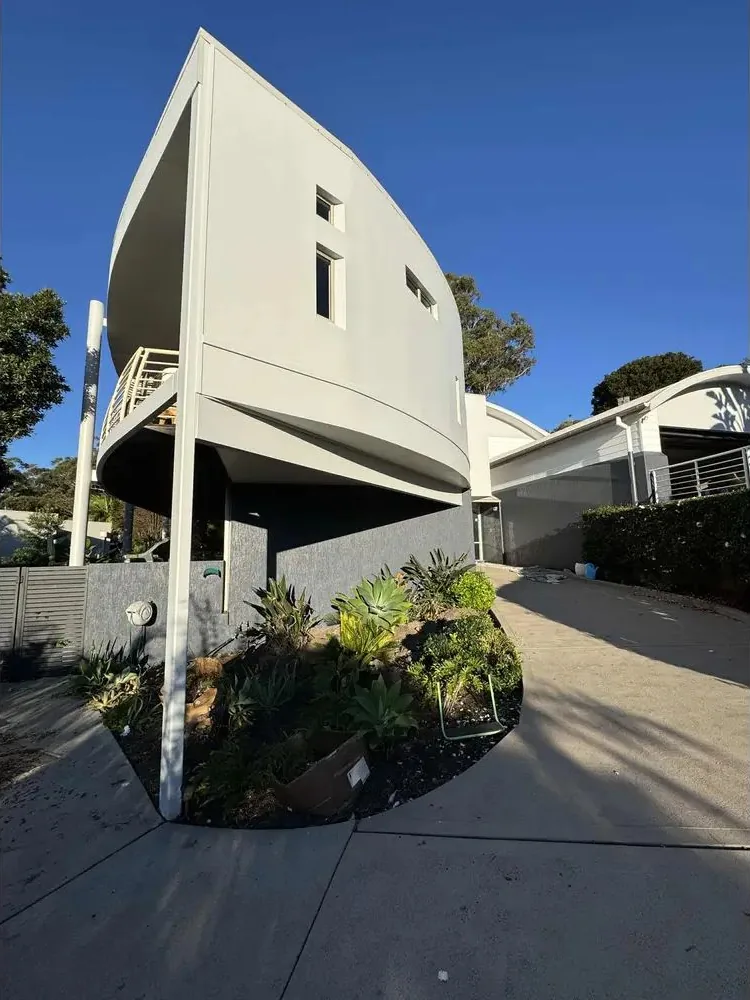Curved contemporary architectural home in Highton with light rendered walls and a dark grey podium wall