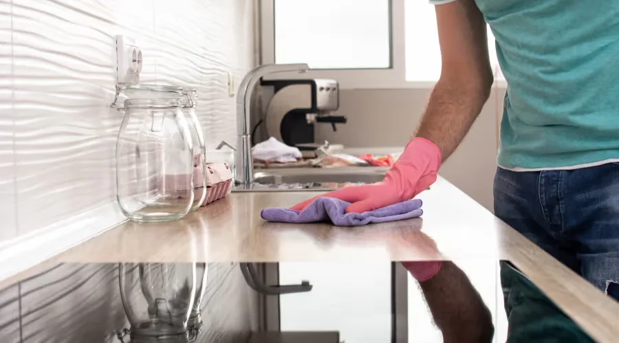 Wiping a kitchen surface clean with a microfibre cloth and gloves