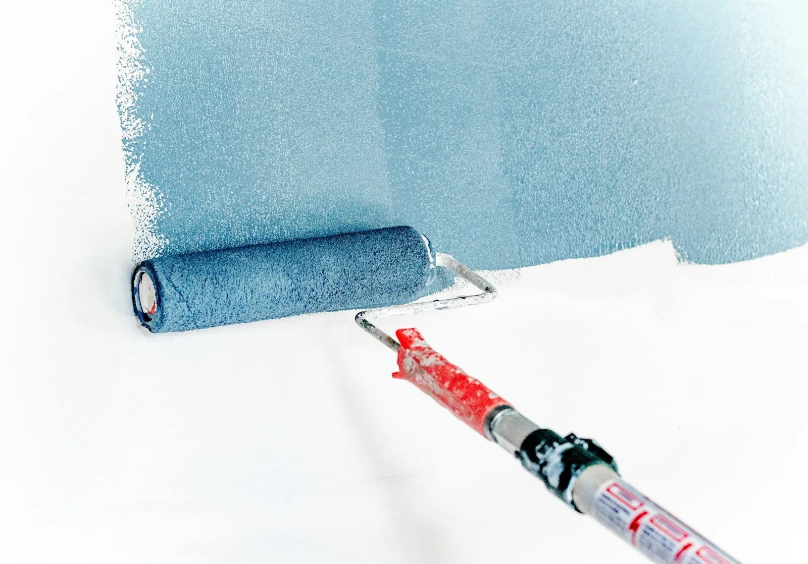 Painter using a roller to apply fresh paint to a home wall